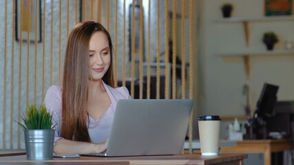 A young woman is sitting at a computer in the office and drinking coffee. Business woman