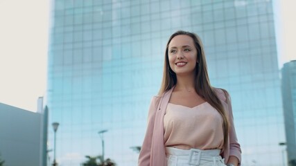 Close-up of a smiling young woman walking to the camera with a phone in her hands on the street