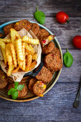 Home made  oven baked meatballs  from  chicken and vegetables and french potato  fries on  wooden background.Bifteki, or spicy meatballs 