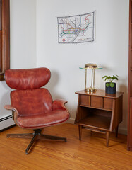 Interior scene with mid-century modern molded walnut shell chair. Vintage red seat and side table with retro lamp.