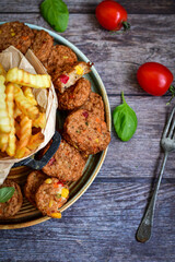 Home made  oven baked meatballs  from  chicken and vegetables and french potato  fries on  wooden background.Bifteki, or spicy meatballs 