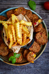 Home made  oven baked meatballs  from  chicken and vegetables and french potato  fries on  wooden background.Bifteki, or spicy meatballs 