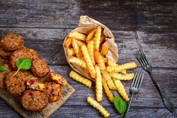 Home made  oven baked meatballs  from  chicken and vegetables and french potato  fries on  wooden background.Bifteki, or spicy meatballs 