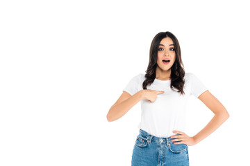 surprised woman pointing with finger at herself while standing with hand on hip isolated on white.