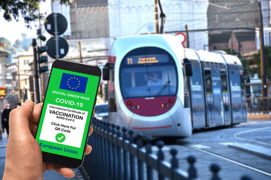 Florence, January 2022: A man at a tram stop is holding smartphone with the European Union digital Green Pass for Covid-19 SARS-CoV-2. Safe travel concept during the Coronavirus pandemic