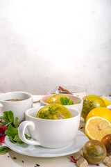 Various tea ball bombs. Assortment of different tea balls with dried tea, cups, lemon and mint, top view copy space. Trendy modern tea variety