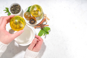 Making tea with Trendy modern tea ball bombs. Tea balls with dried tea, cups, lemon and mint, with classic white cup, top view copy space