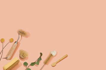 Set of eco friendly zero waste sustainable recyclable cleaning brushes and accessories with green eucalyptus and yellow flower ball on pink background. Alternative household chores. Natural living.