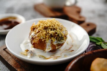 Raj Kachori or Kachouri - Indian deep fried snack stuffed with potatoestopped with yogurt cutneys and sev