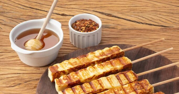 Grilled Rennet or Coalho cheese on a wooden board with sugar syrup and pepper