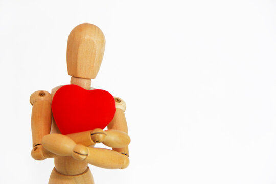 wooden mannequin holding a red heart