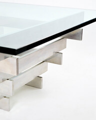 Mid-century modern stacked chrome coffee table with beveled-edge glass top. Geometric minimalist table. Close-up product photograph in white blank space.