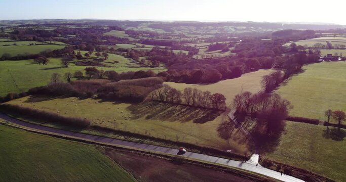 Aerial shot of a car travelling on a road across the East Devon Countryside England on a beautiful sunny day