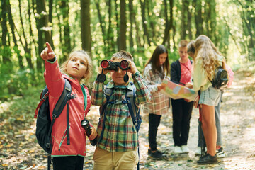 New places. Kids in green forest at summer daytime together