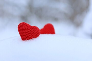 Love hearts, Valentine's card, two red knitted symbols of passion in the snow forest. Background for romantic event, celebration or winter weather