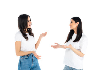 cheerful interracial women in t-shirts and jeans talking isolated on white.