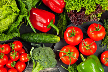 Cabbage, peppers, tomatoes, cucumbers, lettuce, cherry tomatoes, broccoli, arugula on a black background. variety of vegetables on a pile on a wooden table.