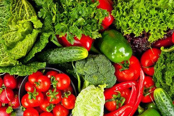 Cabbage, peppers, tomatoes, cucumbers, lettuce, cherry tomatoes, broccoli, arugula on a black background. variety of vegetables on a pile on a wooden table.