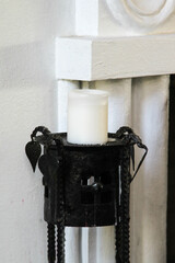 Antique candlestick with a white candle on white wall.