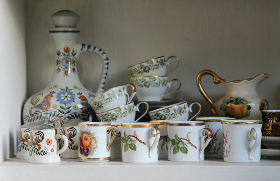 Set of ceramic coffee cups cluttered on the shelf.