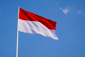 Fototapeta na wymiar The single large red and white Indonesian flag flutters in the strong wind ahead of the 77th Independence Day of the Republic of Indonesia.