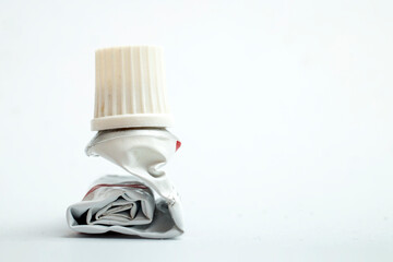 Empty aluminum ointment container tube, squeezed and rolled, side view macro, on white background