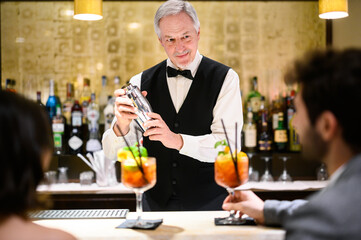 Mature waiter serving cocktails to a couple in a luxury hotel