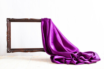 Purple satin curtains unveiling a levitating brown empty frame, on white background