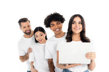 young cheerful woman holding laptop near cheerful interracial friends isolated on white.