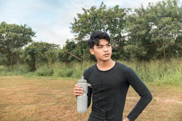 A serious young asian man holding a water