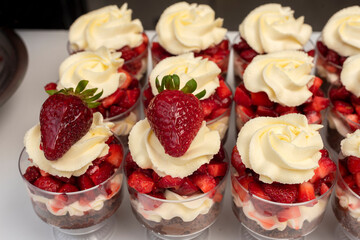 Pastry chef preparing step by step delicious dessert black forest or chip with chocolate biscuit, cream and fresh strawberries in shot glasses