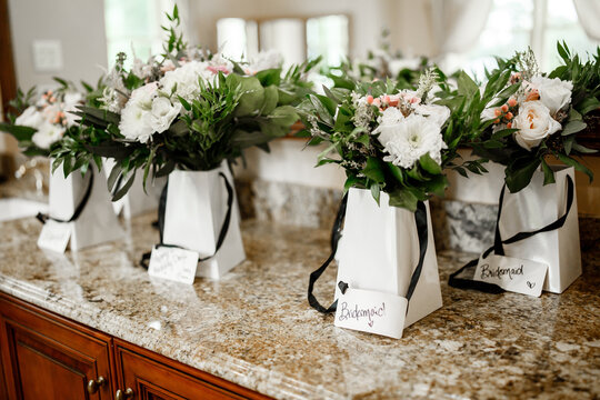 White packages with bouquets of flowers and greenery stand on the table Private presents for bridesmaids or guests Nominal bouquets of flowers Mirror background