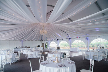 A wide-angle view of a wedding reception venue with dance floor and surrounding tables A large...