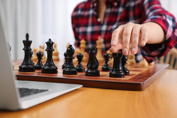 Woman playing chess with partner through online video chat at table indoors, closeup