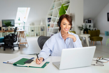 Attractive businesswoman having online meeting while sitting behind her laptop at office desk