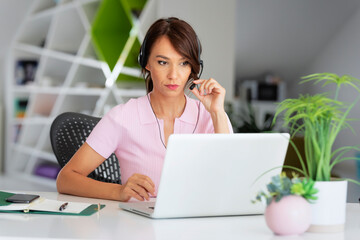 Attractive businesswoman having online meeting while sitting behind her laptop at office desk