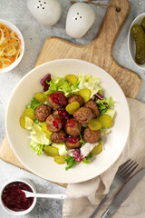 Swedish meatballs with salad, pickled cucumber and lingonberry jam in a bowl. A traditional...