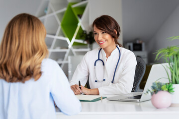 Female doctor consulting her patient while sitting at desk in doctor's office