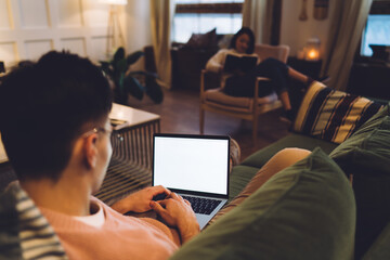 Woman reading book while boyfriend using laptop