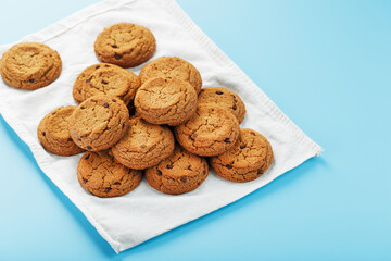 Oatmeal cookies on a blue background and a white napkin top view