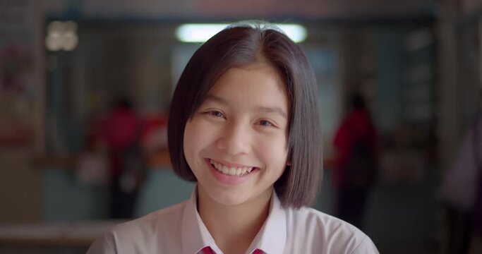 Slow motion scene of a young Asian teenage high school student girl is smiling happily.	