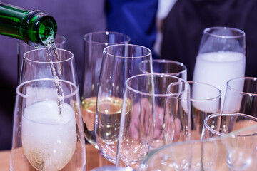 A man pours champagne into glasses in close-up. - 479794424