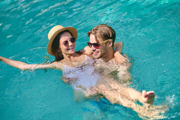 Young couple swimming in a pool and feeling excited