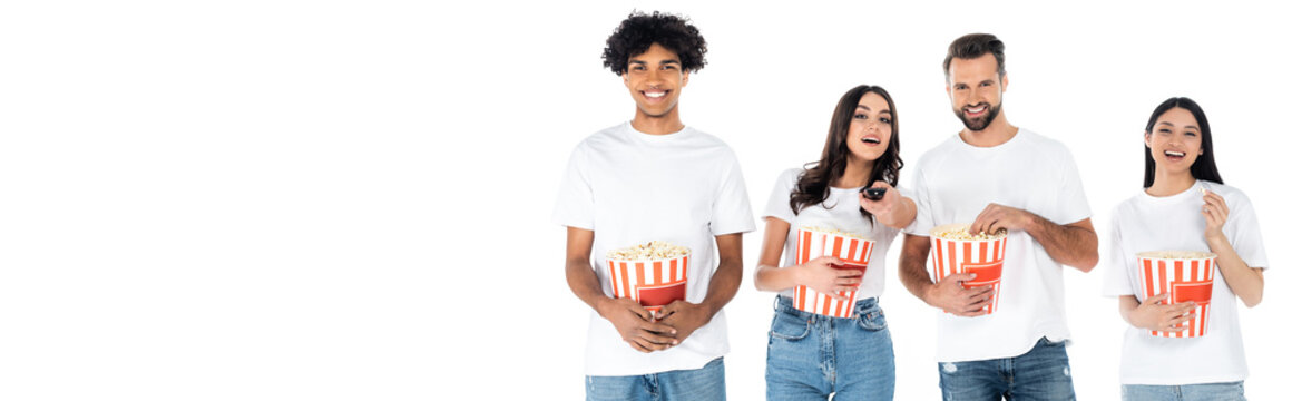 joyful multiethnic friends eating popcorn while watching movie isolated on white, banner.