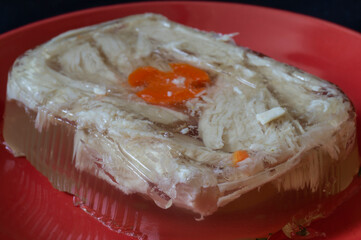 Aspic chicken meat on a red plate