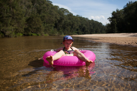 Young girl sitting on a pink inflatable in a river