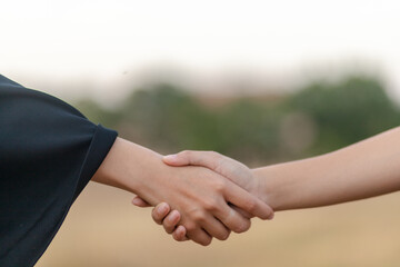 Woman holding hands between two coworkers with good relationship concept in natural background.