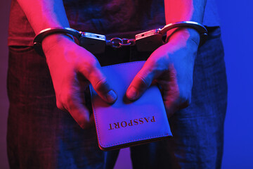 Man in handcuffs with a passport in his hands, the concept of arrest for forging documents - obrazy, fototapety, plakaty