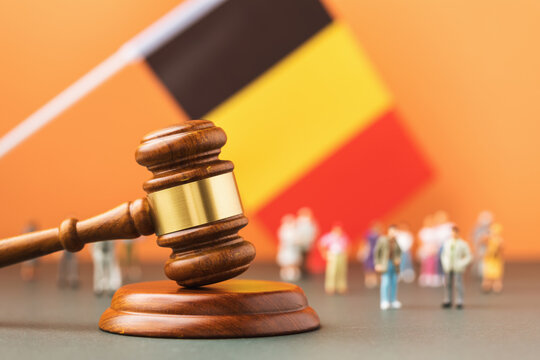 Wooden judge gavel, flag and plastic toys on a colored background, the concept of litigation in the Belgian society
