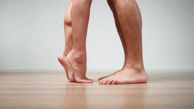 Close-up. Unrecognizable people. A loving married couple barefoot approach each other and hug. Female and male legs. Love and relationship concept.